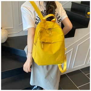 Détail d'un sac à dos en nylon jaune vif avec logo M porté par un mannequin décontracté
