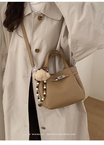 Detail of khaki pebbled leather bucket bag with metal turn-lock and cute bead charm
