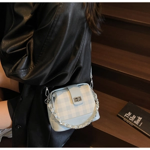 Close-up of light blue checkered crossbody bag with silver chain and glossy finish