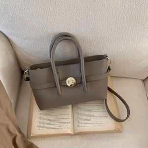 Detail of grey pebbled leather handbag with gold rotary buckle and dual handles