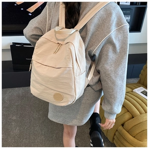 Gros plan d'un sac à dos en nylon beige avec double fermeture éclair au dos d'un mannequin