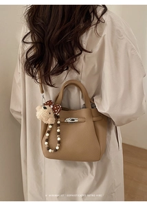 Brown lychee leather bucket bag with lock detail, teddy bear charm and beaded strap
