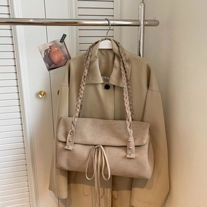 Close-up of khaki suede tote bag with braided shoulder strap and drawstring detail