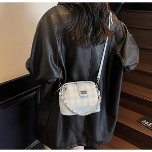 Detail of blue checkerboard doctor bag with silver twist lock and metal chain strap
