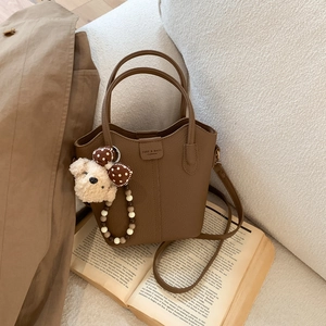 Braune Bucket Bag Details mit Litschi-Ledertextur und Plüsch-Teddybär-Anhänger