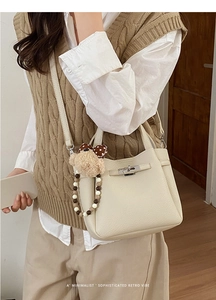 Chic cream litchi leather bucket bag with plush bear charm and metallic turn-lock closure