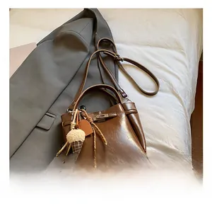 Detail view of a vintage dark brown leather bucket bag with an ice cream plush charm