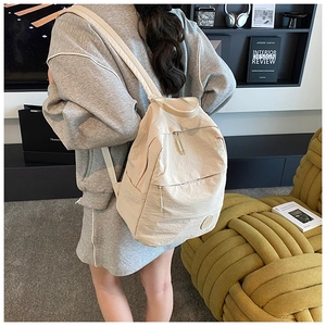 Détail d'un sac à dos crème léger avec poches latérales et texture en nylon durable