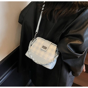 Detail of blue plaid crossbody bag featuring silver metal twist lock and chunky chain strap