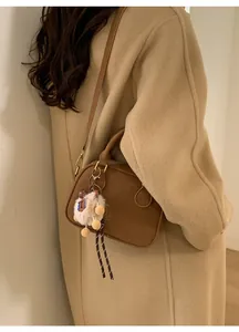 Detail of vintage brown suede bowling bag with shoulder strap and plush sheep charm