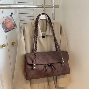 Detail of dark coffee suede tote bag featuring braided strap and silver rivets accents