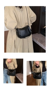 Close-up of black lychee leather crescent bag with chain handle and long strap