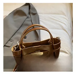 Detail of a brown leather bucket bag with metal buckle and comfortable handle