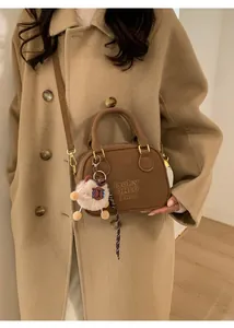 Detail of vintage brown bowling bag with embossed lettering and plush sheep charm