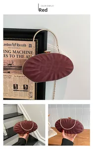 Detail of burgundy shell-shaped evening clutch with pleated texture and gold handle
