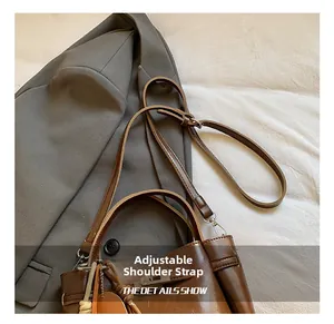 Detail of deep brown bucket bag showing the adjustable leather strap and metal buckle