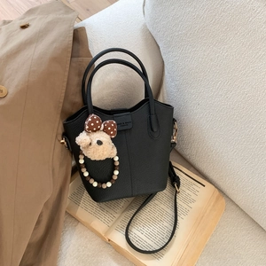 Detailansicht der schwarzen Lederbeuteltasche mit Bärenanhänger und goldener Hardware-Optik