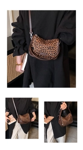 Detail view of leopard print saddle bag with brown leather trim and metal logo plaque