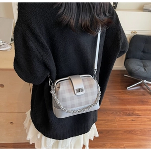 Detail of silver checkered crossbody bag with silver chain and twist lock on the shoulder