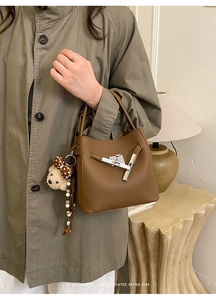 Brown lychee leather bucket bag with silver metal buckle and bear charm detail