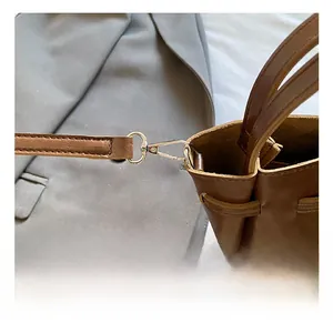 Detail of premium metal lobster clasp and detachable strap on brown leather bucket bag