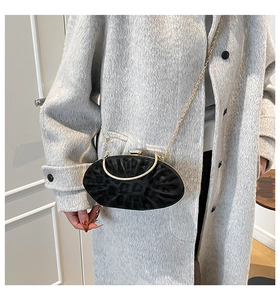 Detail of elegant black velvet evening clutch bag with gold handle and chain strap