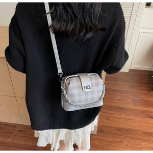 Macro shot of stylish silver-grey checkered bag with metallic chain and leather strap