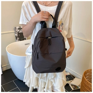 Détail du sac à dos en nylon noir avec poignée et logo dans un décor intérieur artistique