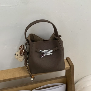Detail of dark brown bucket bag featuring pebble leather and silver metal knot buckle