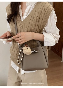 Detail view of taupe bucket bag with silver lock and plush bear charm decoration