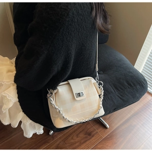 Detail of beige checkered crossbody bag with silver chain strap and metallic rotary lock