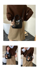 Detail of black glossy bucket bag with silver lock and plush ice cream pendant charm