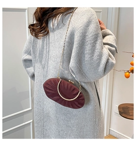 Detail of burgundy pleated oval handbag with gold chain strap and metal handle