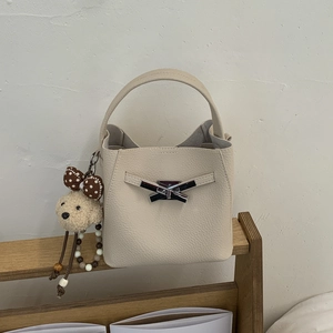 Detailed macro of a cream bucket bag with lychee grain leather and silver bow lock