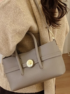 Grey pebbled leather handbag with gold twist lock shown on model for daily commuting style