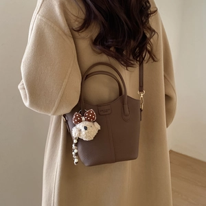 Detailaufnahme der dunkelbraunen Eimer-Tasche aus Leder mit beige Teddybär Anhänger