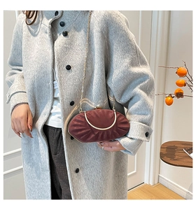 Close-up of elegant pleated dark red shell clutch with gold metal trim and chain