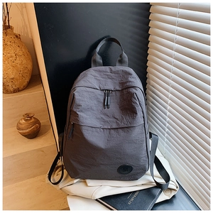 Gros plan d'un sac à dos léger en nylon gris foncé avec texture plissée et logo M