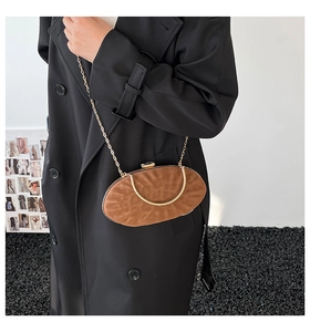 Detail of brown oval clutch bag with wavy texture, gold chain and metal handle