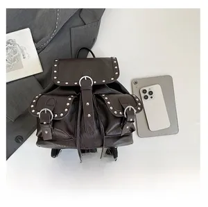 Détail d'un sac à dos en cuir marron foncé avec clous et poches avant sur un bureau