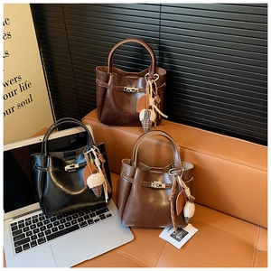 Close-up of vintage bucket bags in black and brown with metallic locks and charms