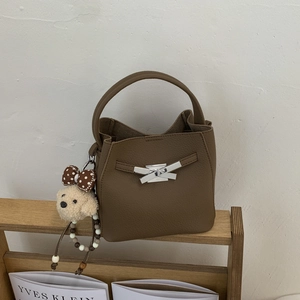 Macro view of brown lychee grain leather bucket bag with silver metal bow clasp