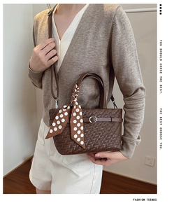 Detailed view of brown woven crossbody bag with polka dot scarf and silver buckle