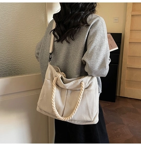 Detail of off-white corduroy tote bag showing textured fabric and woven rope handles