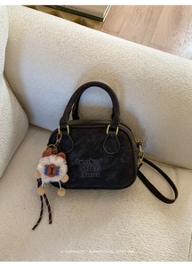 Close-up of retro brown bowling bag with embossed branding and plush charm detail