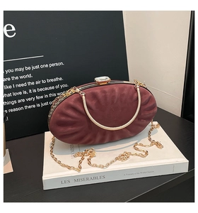 Detail view of burgundy satin shell clutch bag with crystal clasp and gold chain strap