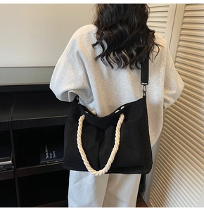 Detail view of a black corduroy large capacity bag with thick rope handles on a model