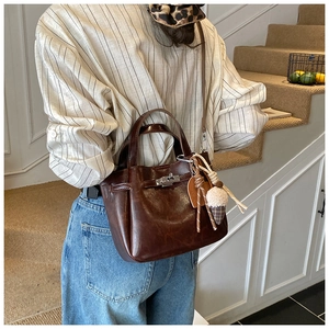 Detailed view of deep brown vintage leather bucket bag with silver metal buckle and charms