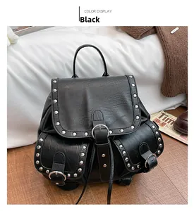 Détail d'un sac à dos vintage en cuir noir avec rivets argentés sur sol en bois