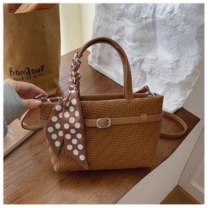 Detail of caramel brown woven leather handbag with silk scarf wrap and silver buckle